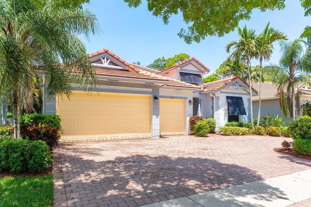 a view of an empty room with chandelier fan and kitchen view