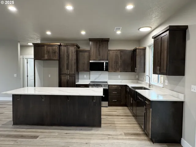 a large kitchen with stainless steel appliances kitchen island granite countertop a sink counter space and cabinets