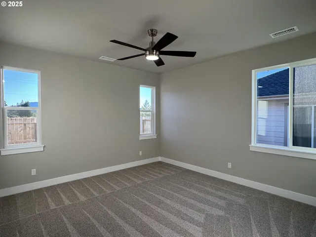 an empty room with windows and fan