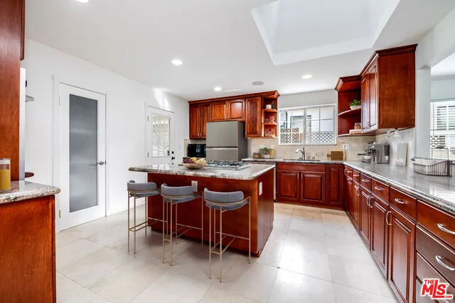 a large kitchen with stainless steel appliances granite countertop a stove a sink and a refrigerator