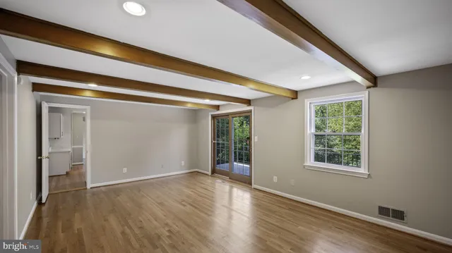 a view of an empty room with wooden floor and a window