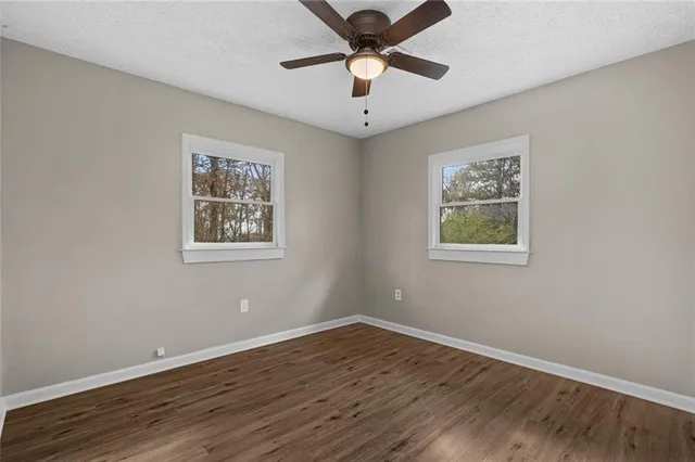 a view of empty room with wooden floor and fan