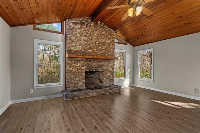 a view of an empty room with wooden floor fireplace and a window
