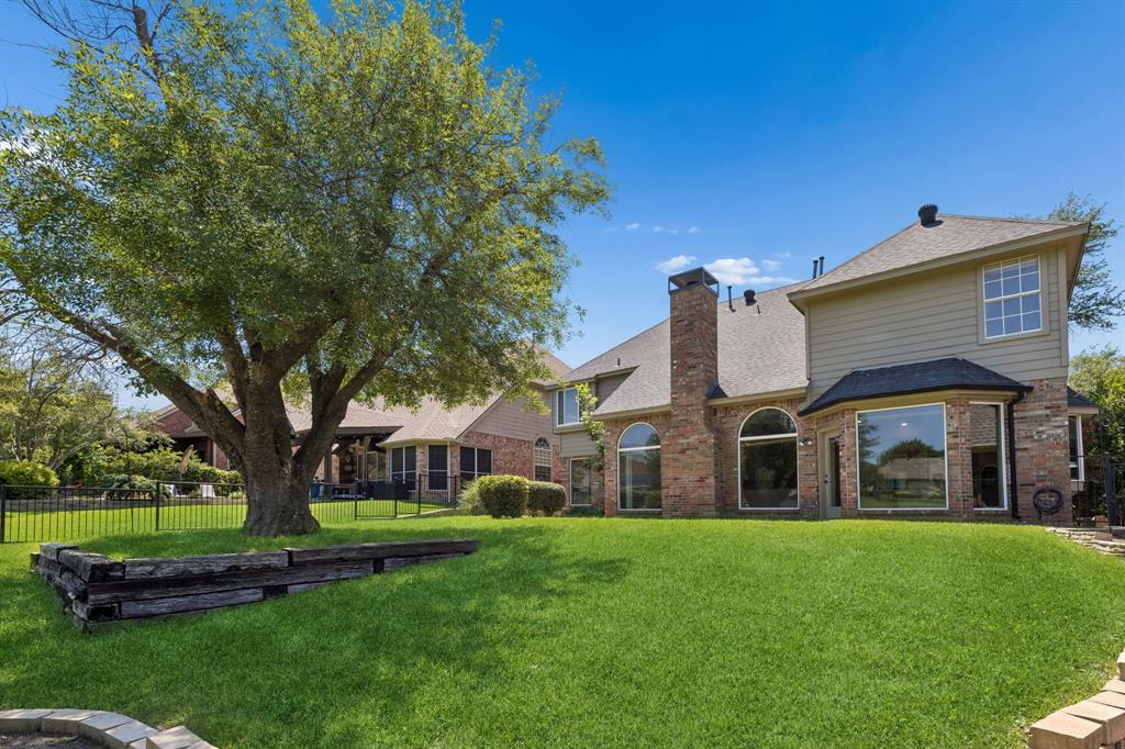 2925 Sunset Ridge McKinney, TX 75072 - Photo 33 of 33 Spectacular backyard showcasing timeless brick architecture, dramatic arched windows, mature landscaping, and breathtaking golf course frontage in a truly picturesque setting.