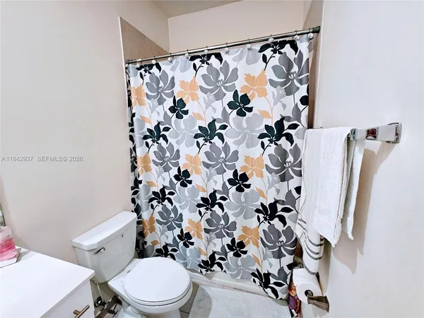 a white toilet sitting next to a shower curtain