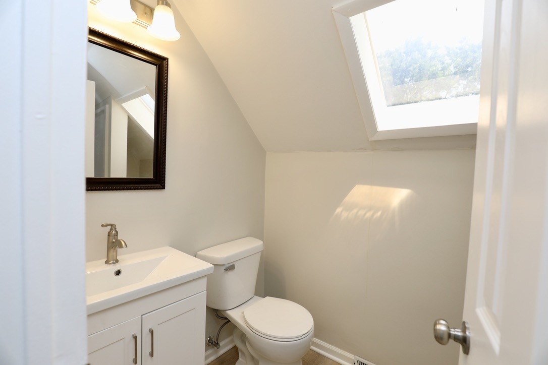 544 Spruce Road Bolingbrook, IL 60440 - Photo 10 of 13 a bathroom with a toilet a sink a mirror and a window