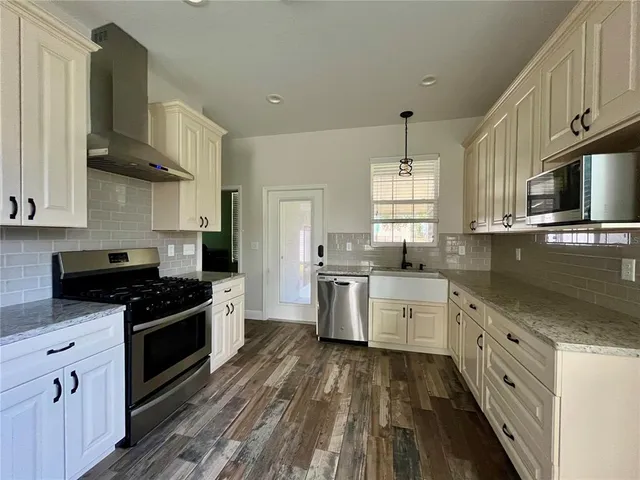 a kitchen with granite countertop a stove top oven a sink dishwasher and a refrigerator