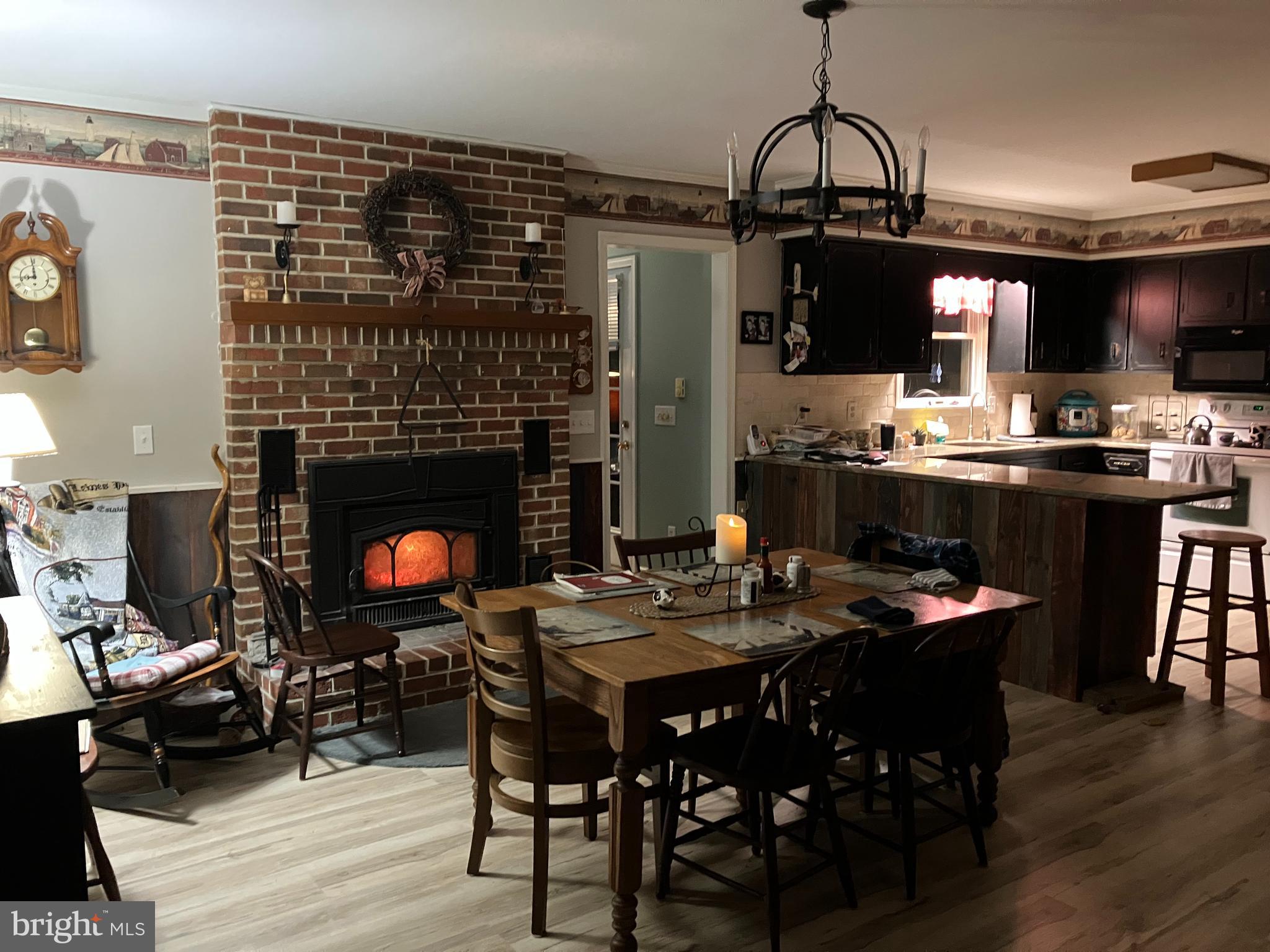 28736 Stockley Road Milton, DE 19968 - Photo 9 of 35 a dining room with wooden floor a fireplace a glass table and chairs