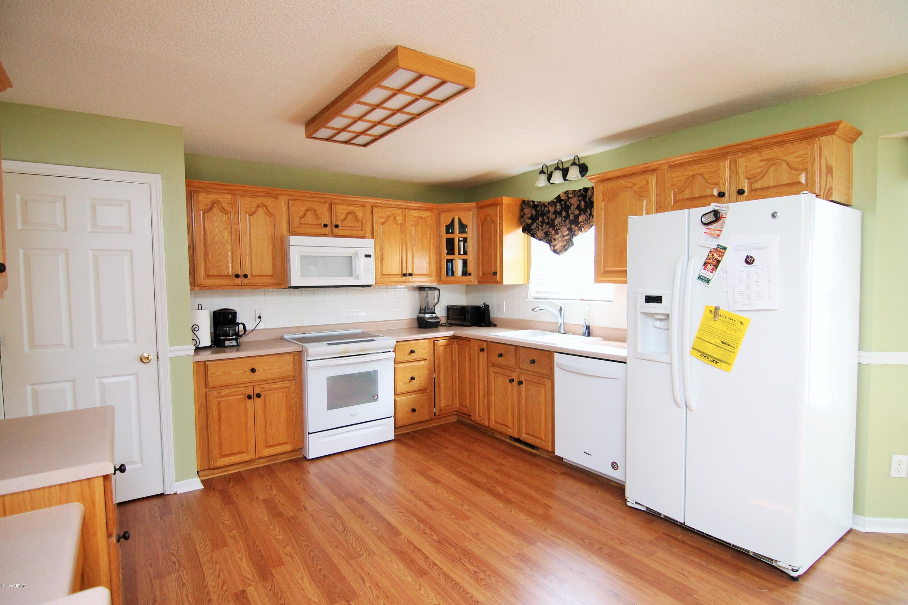226 Ruben Road Byron, GA 31008 - Photo 12 of 30 a kitchen with a refrigerator a stove top oven a sink and dishwasher with wooden floor