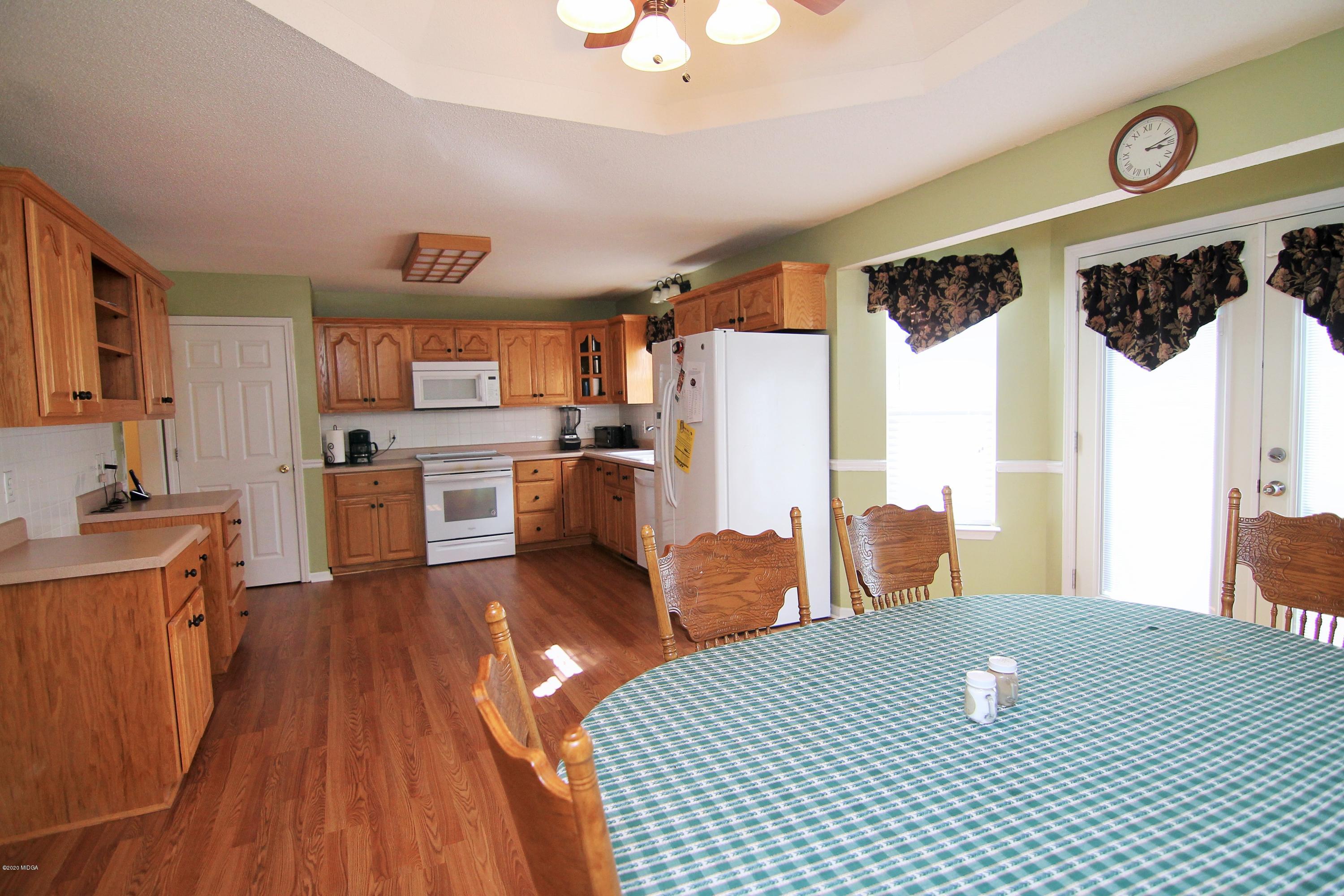 226 Ruben Road Byron, GA 31008 - Photo 9 of 30 a kitchen with stainless steel appliances granite countertop a refrigerator a sink dishwasher a dining table and chairs with wooden floor