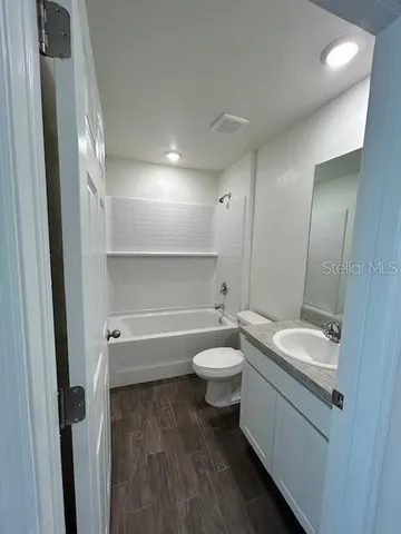 a bathroom with a granite countertop toilet a sink and a mirror