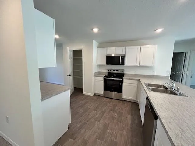 a kitchen with granite countertop a stove top oven a sink dishwasher and a refrigerator with wooden floor