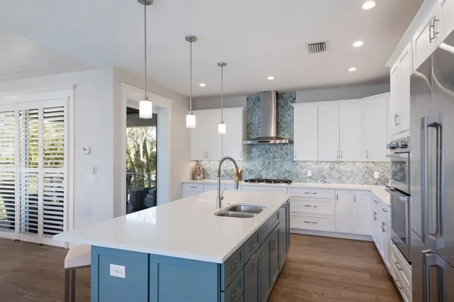 a kitchen with stainless steel appliances kitchen island granite countertop a sink a stove a refrigerator cabinets and chairs