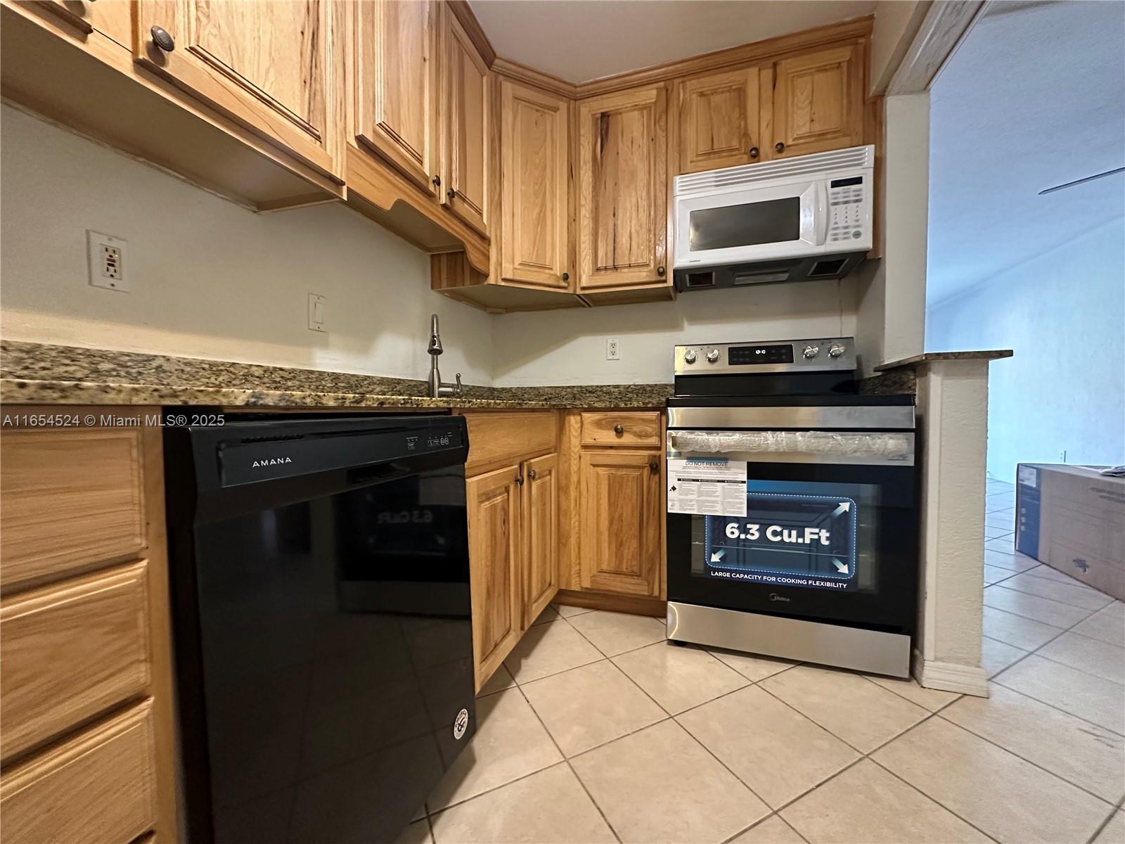 8650 Southwest 67th Avenue, Unit 1032 Pinecrest, FL 33156 - Photo 2 of 16 a kitchen with stainless steel appliances granite countertop a stove top oven microwave and cabinets