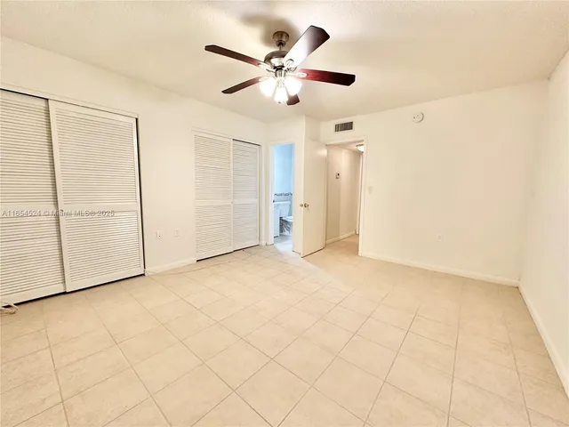 an empty room with ceiling fan and window
