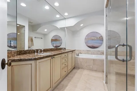 a bathroom with a granite countertop sink a mirror and shower