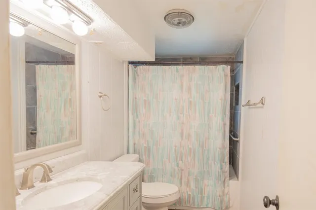 a bathroom with a granite countertop sink toilet and shower