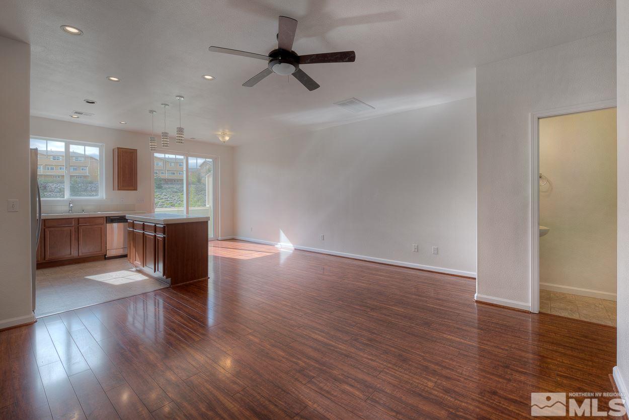 4800 Ciarra Kennedy Lane Reno, NV 89503 - Photo 6 of 25 an empty room with wooden floor a ceiling fan and kitchen view