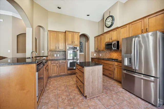 a kitchen with stainless steel appliances granite countertop a refrigerator a stove top oven a sink and dishwasher
