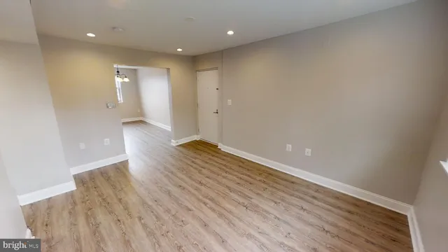 a view of a hallway with wooden floor and a bathroom
