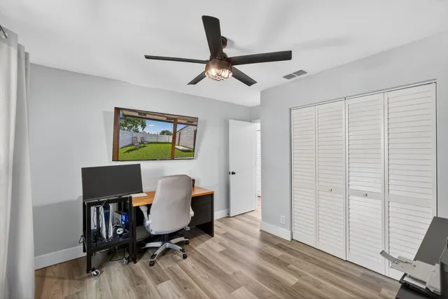 a workspace with wooden floor a ceiling fan and a window