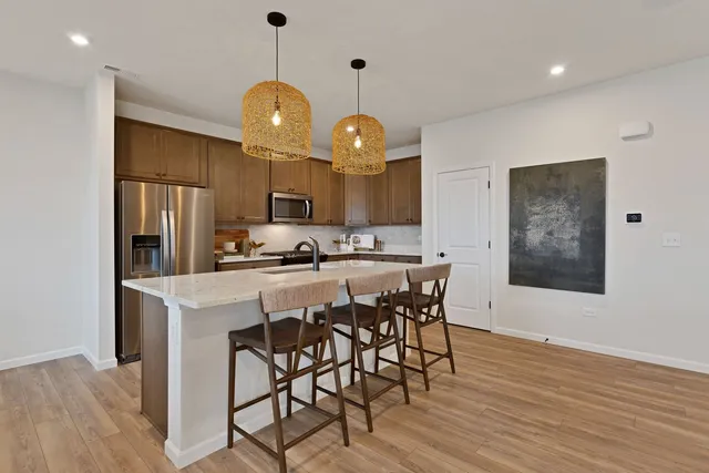 a kitchen with stainless steel appliances a dining table chairs and wooden floor