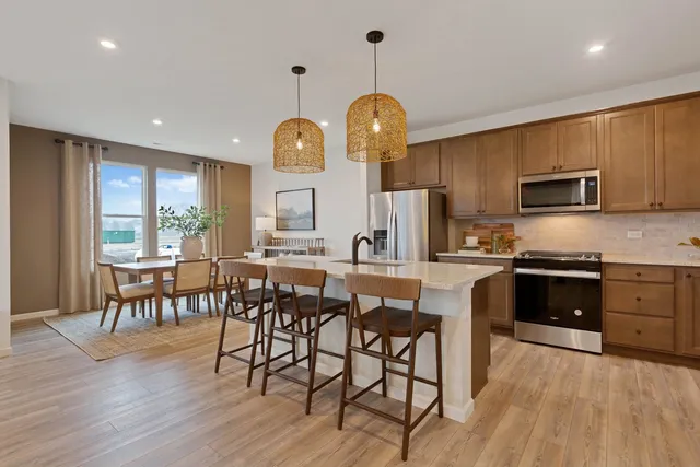 a kitchen with stainless steel appliances a dining table chairs stove microwave and cabinets