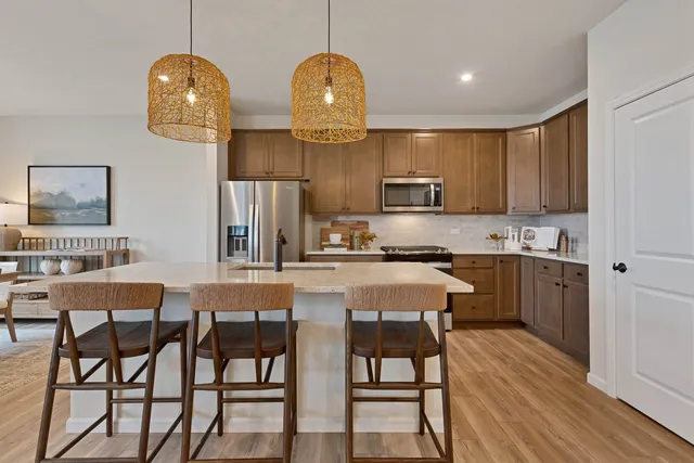 a kitchen with stainless steel appliances granite countertop a stove a sink dishwasher a dining table and chairs with wooden floor