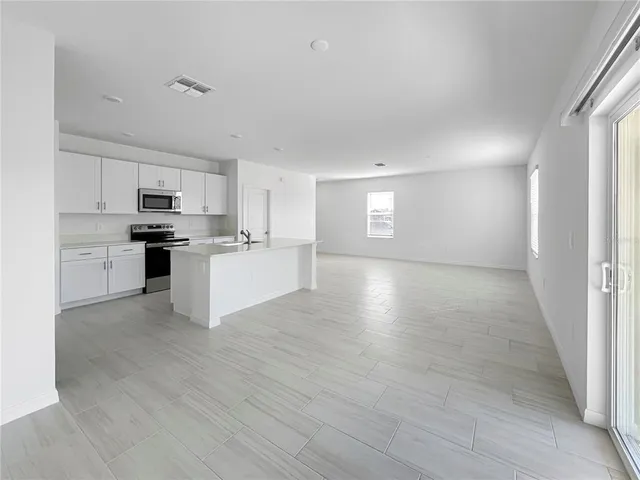 a view of a kitchen with a sink a refrigerator and cabinets