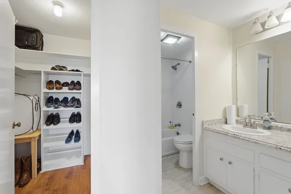 a walk in closet with wooden floor