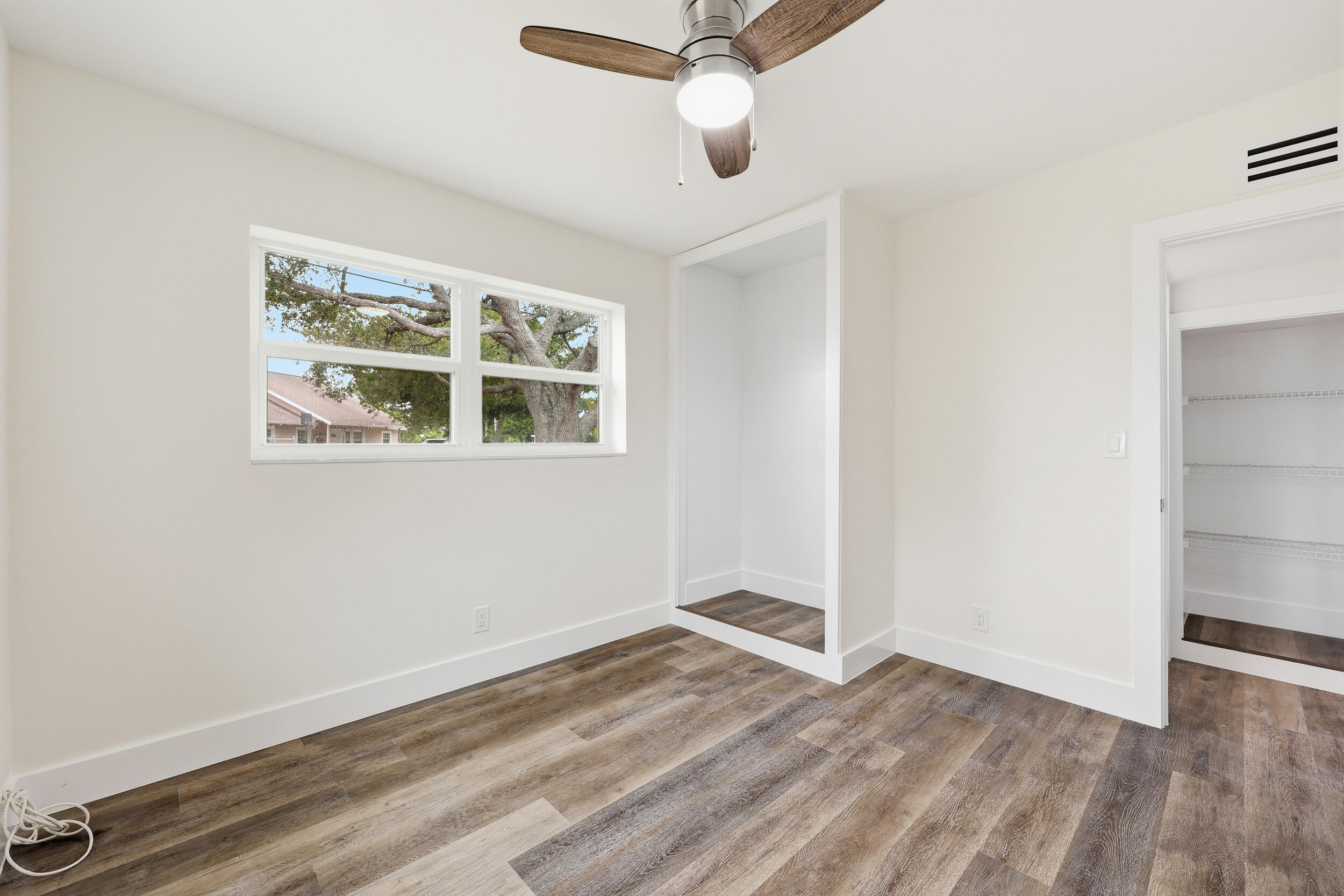 403 Todd Street Jupiter, FL 33458 - Photo 18 of 30 an empty room with wooden floor fan and windows