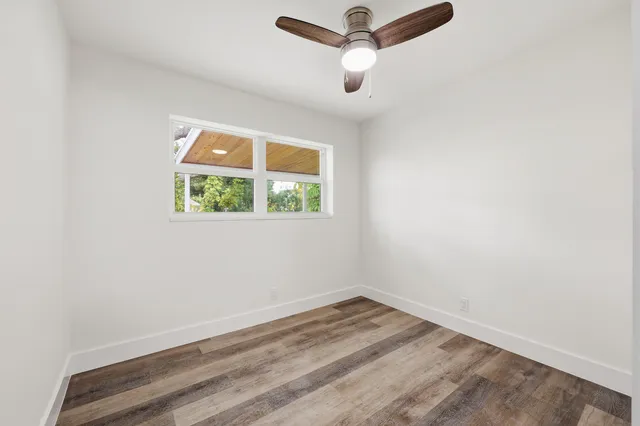 an empty room with a window and a ceiling fan
