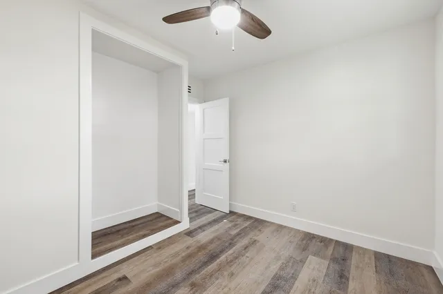 an empty room with a hardwood and ceiling fan