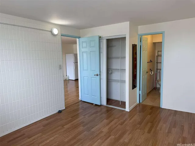 an empty room with wooden floor & windows