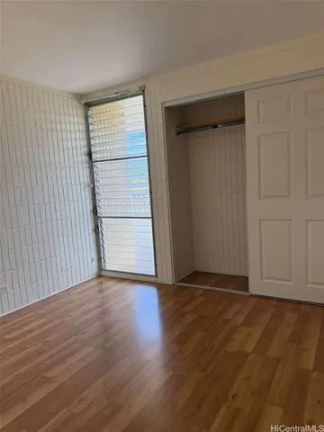 a view of an empty room with wooden floor and closet