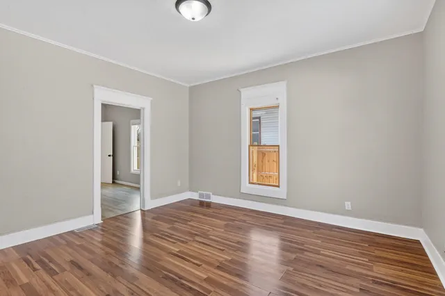 a view of an empty room with wooden floor and a window