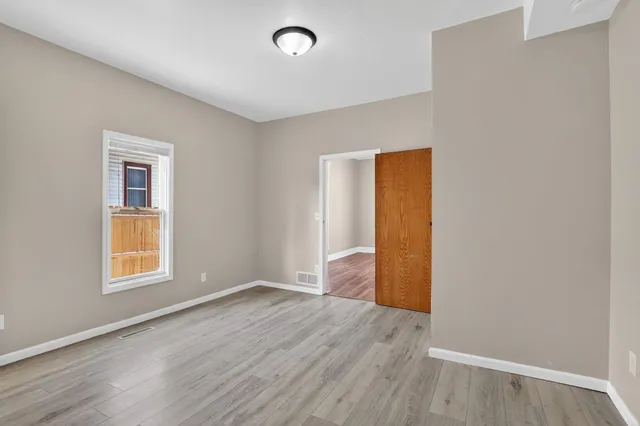 an empty room with wooden floor and windows