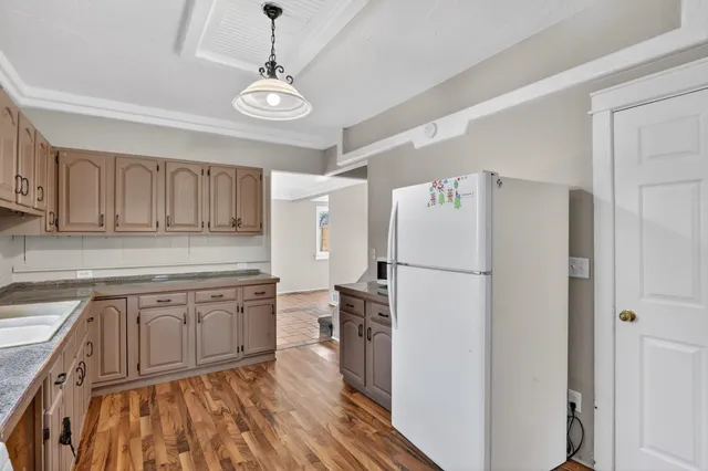 a kitchen with stainless steel appliances granite countertop a refrigerator a sink dishwasher a dining table and chairs with wooden floor