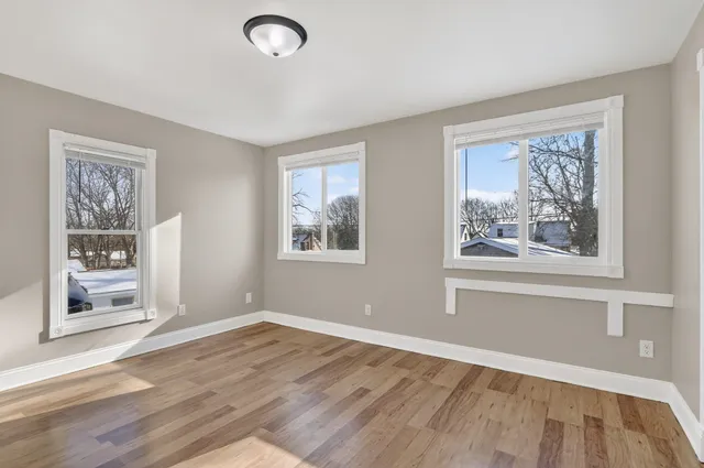 a view of empty room with window and wooden floor