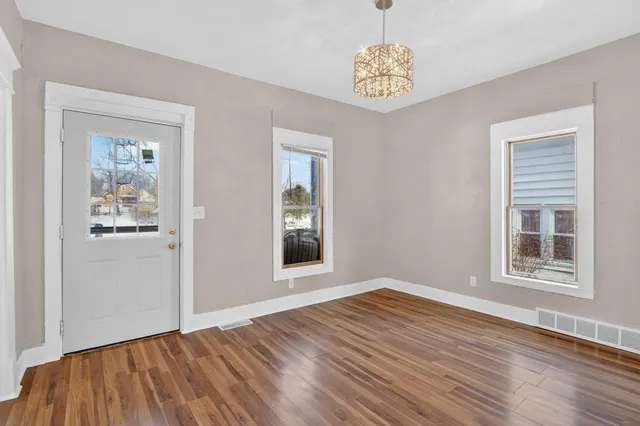 a view of an empty room with window and wooden floor