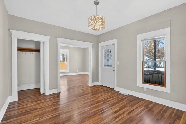 a view of an empty room with wooden floor and a window