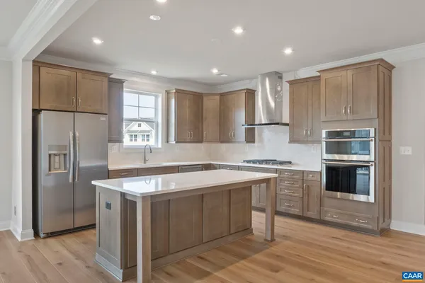 a kitchen with stainless steel appliances granite countertop a stove a refrigerator a sink and white cabinets with wooden floor