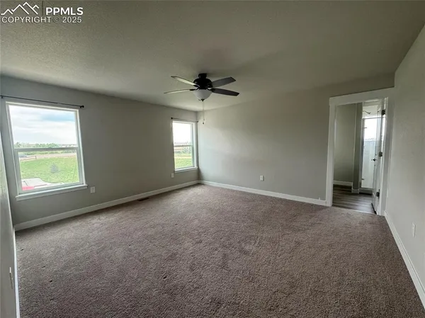 an empty room with windows and a ceiling fan