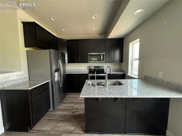a kitchen with stainless steel appliances granite countertop a refrigerator a sink a stove a microwave and wooden cabinets