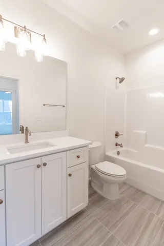 a bathroom with a double vanity sink a toilet and a bathtub
