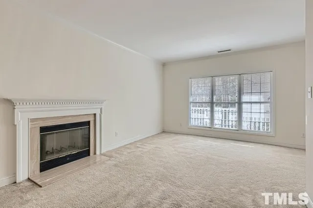 an empty room with a fireplace and windows