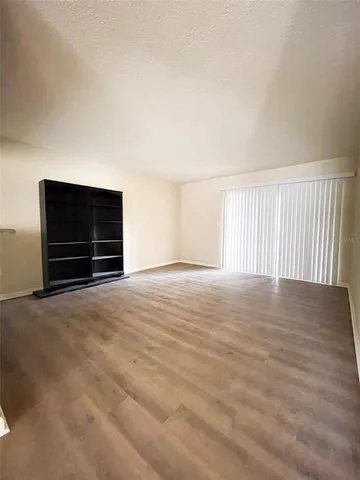 a view of an empty room with wooden floor and window