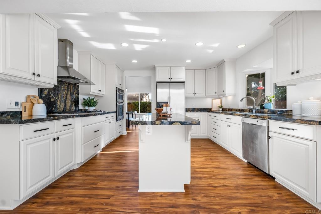 1592 Hawk View Drive Encinitas, CA 92024 - Photo 5 of 55 a kitchen with kitchen island granite countertop wooden floors stainless steel appliances and white cabinets