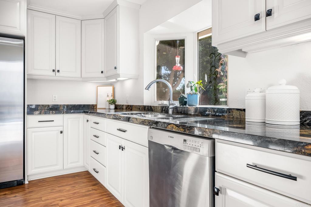 1592 Hawk View Drive Encinitas, CA 92024 - Photo 7 of 55 a kitchen with granite countertop white cabinets and white appliances