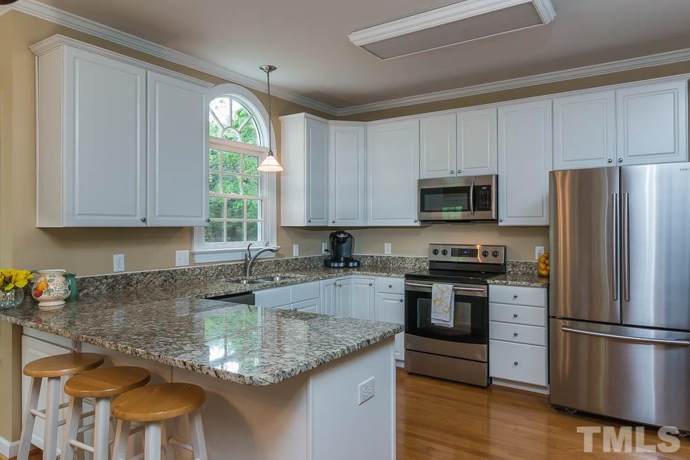 2908 Sunnystone Way Raleigh, NC 27613 - Photo 9 of 25 a kitchen with stainless steel appliances granite countertop a refrigerator sink and stove